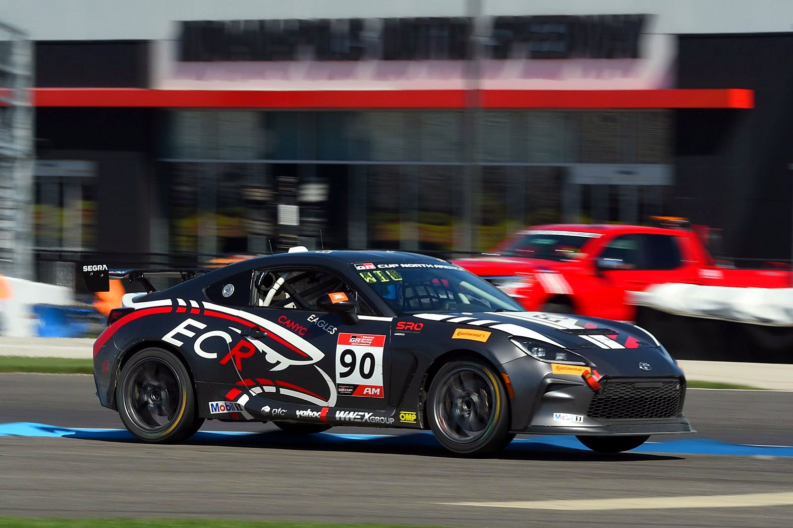 The #90 GR86 cornering past a pit lane building