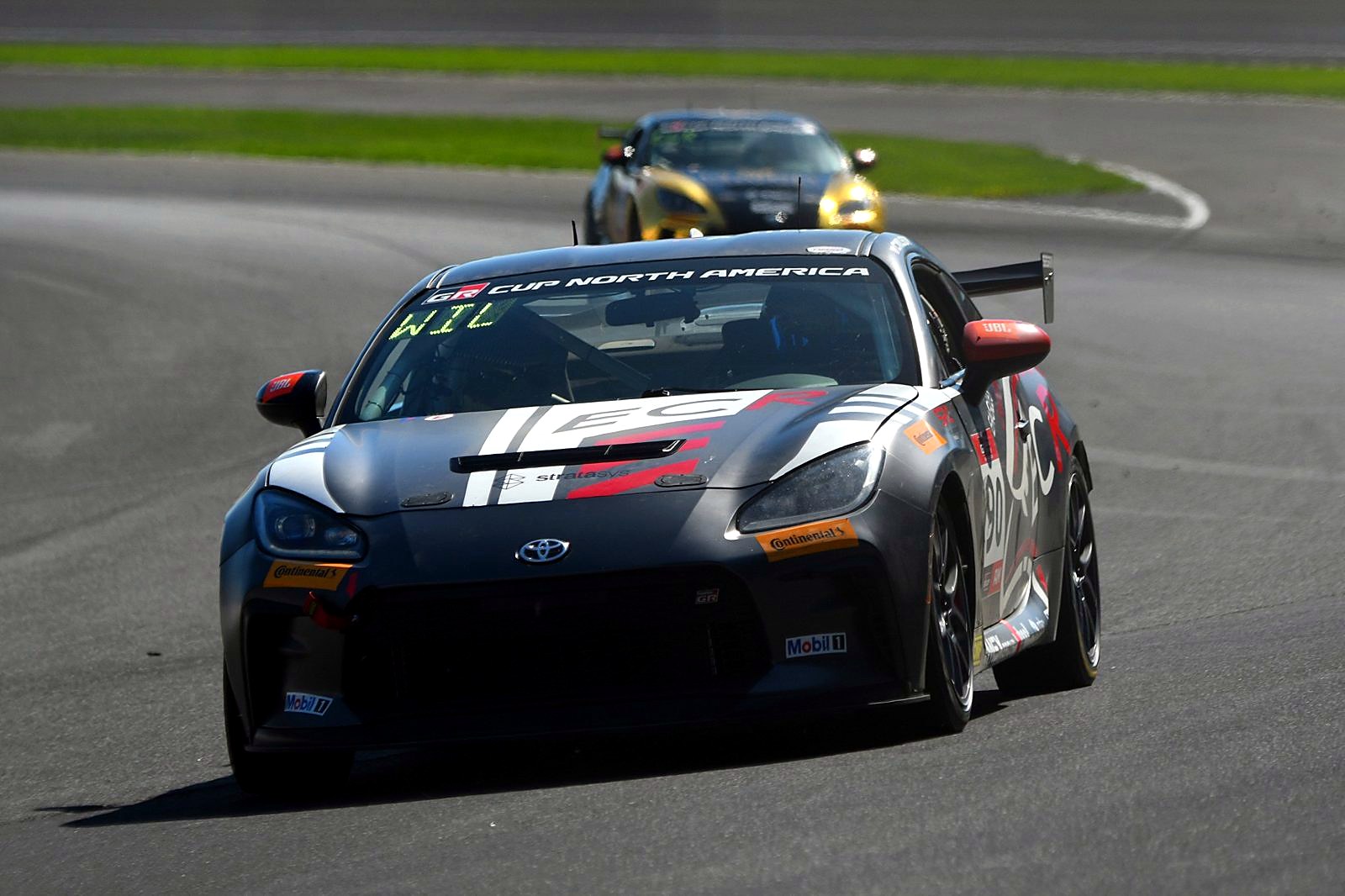 Front view of the #90 GR86 leading another car through a turn