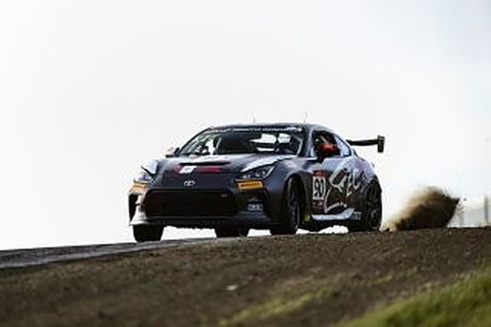 The #90 kicking up dirt over a crest at Sonoma